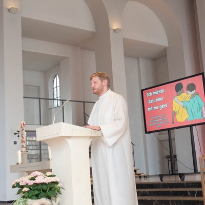 Ein Priester spricht in einer Kirche an einem Lesepult.