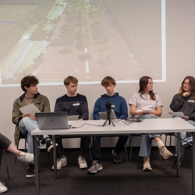 Mehrere Jugendliche sitzen bei einer Gespr&auml;chsrunde vor einer projizierten Pr&auml;sentation.