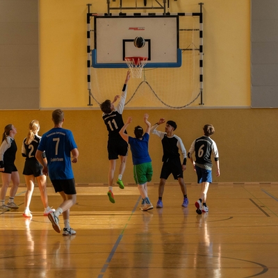 Jugendliche und Lehrkr&auml;fte beim Basketballspiel in der Sporthalle.